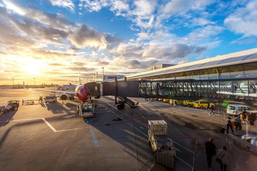 Airport terminal with aircraft and passengers representing reliable airport transport service in Dubai by Alsinan Transport