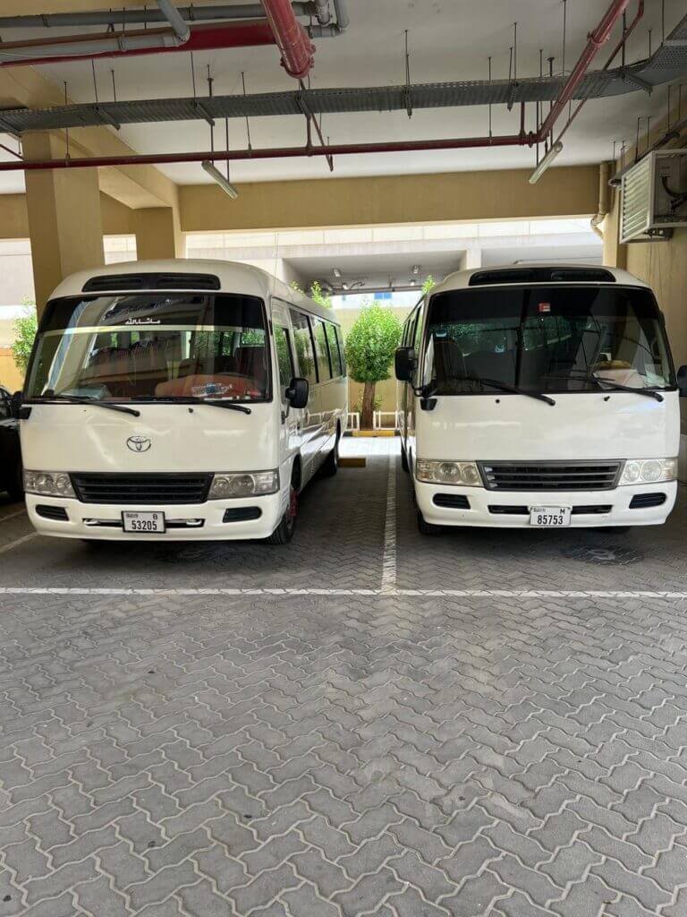 Two Toyota Coaster minibuses used for reliable group and staff transport services in Dubai by Alsinan Transport
